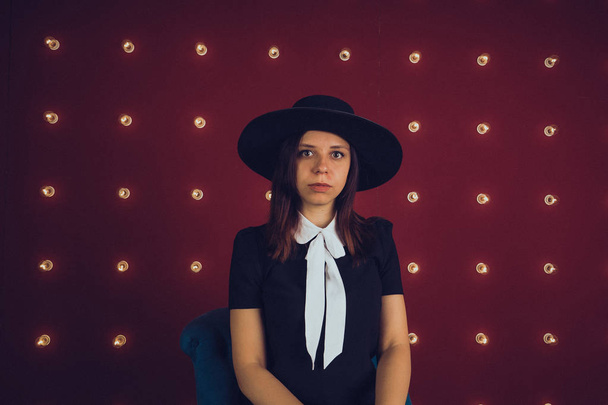 Girl in black dress and black hat posing on red background - Foto, immagini