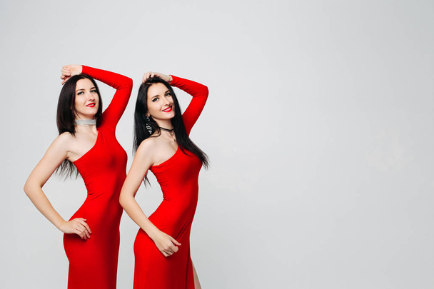 Twee sexy zusters Tweelingen in rode jurken. - Foto, afbeelding