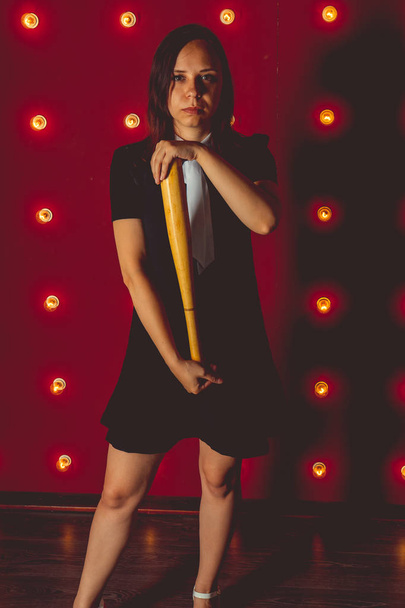 girl posing on a red background with a baseball bat in his hands, the concept of a bully or athletes - 写真・画像