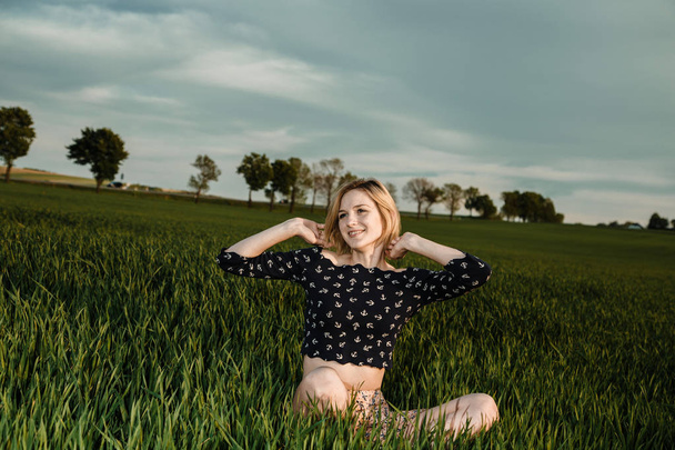 Jong meisje in een groene veld. Stijlvolle meisje. Groen gras en een blauwe hemel. Emotionele vrouw. plener. Reizen. - Foto, afbeelding