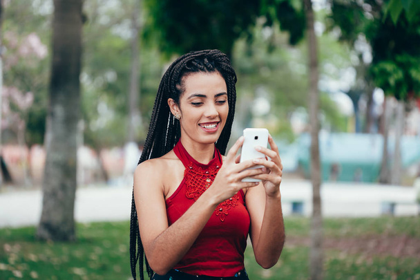 Szép afro amerikai nő segítségével mobil a parkban. Kommunikáció fogalma. - Fotó, kép