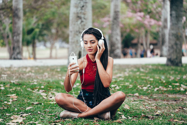 Pretty girl listening music with her headphones in the park - Zdjęcie, obraz