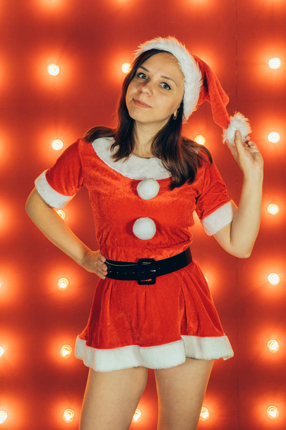 Večírek, oslava, Vánoce a nový rok. Krásná dívka, která nosí červené čepice Santa Claus. Smyslný vánoční dívka na červeném pozadí. Sexy Santa pomocník dívka. Nový rok, Vánoce, sváteční výzdobou. - Fotografie, Obrázek