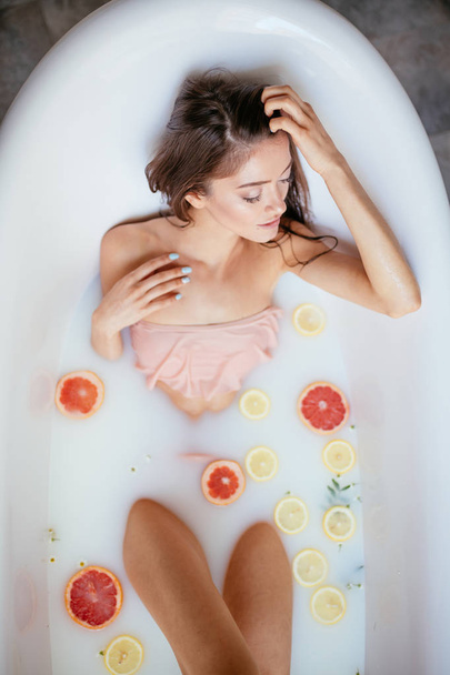 A young brunette woman takes a milk bath. - Φωτογραφία, εικόνα