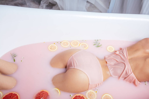 Dokonalé ženské hýždě zblízka v krajkové kalhotky v mléčné vaně s pomeranči - Fotografie, Obrázek