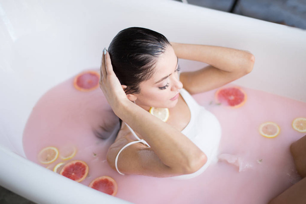 Woman relaxing in milky bath in spa resort. Wellness and Wellbeing concept - Foto, afbeelding