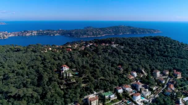 Mediterrán falu közelében szép napsütésben fény zöld dombjai között. háztetők és szűk utcáira lehet kitekinteni. hegyek és a tenger, a távolban. Nyáron Franciaországban a 4 k drone légifelvételek - Felvétel, videó