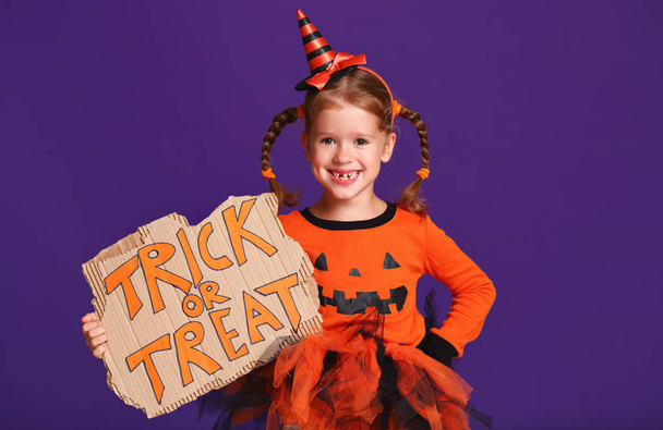 happy Halloween! cheerful child girl in costume with pumpkins on a violet purple backgroun - Photo, Image