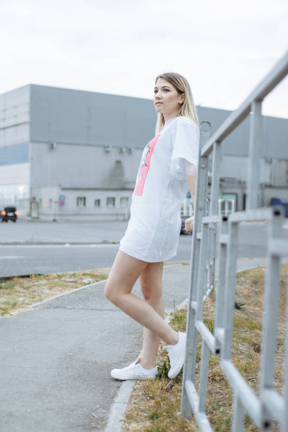 Beautiful woman with nude legs walking around city street wearing long white shirt and jacket - Valokuva, kuva