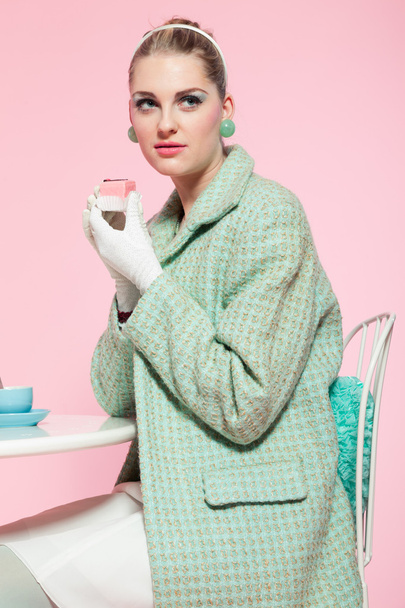 lány szőke haj ötvenes években divat stílus eszik csésze sütemény. - Fotó, kép