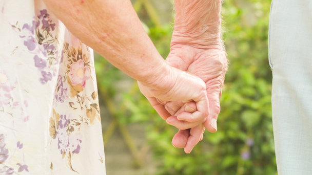 Vue à angle bas d'un couple caucasien âgé affectueux se tenant la main dans leur jardin
 - Séquence, vidéo