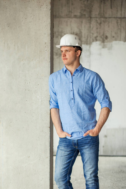 pensive gorgeous builder is standing with arms on the pockets - Foto, afbeelding