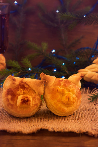 Dwie głowy wieprzowe - symbol 2019 z ciasta francuskiego na obrus lniany, ramy pionowej, deser na Boże Narodzenie.  - Zdjęcie, obraz