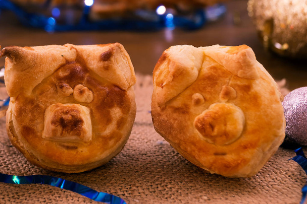 Две запеченные свиные головы из слоеного теста на льняной салфетке являются символом 2019 года
. - Фото, изображение