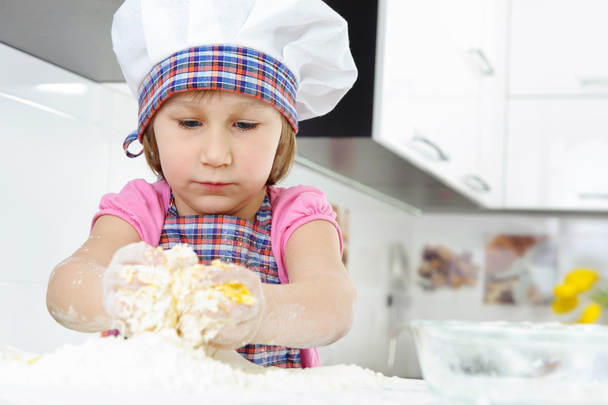 Little girl in baker hat cooking - Photo, image