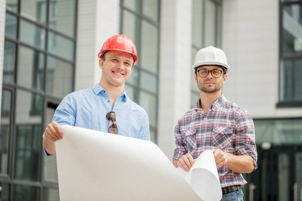 two young talented engineers are holding scheme of construction - Foto, Bild