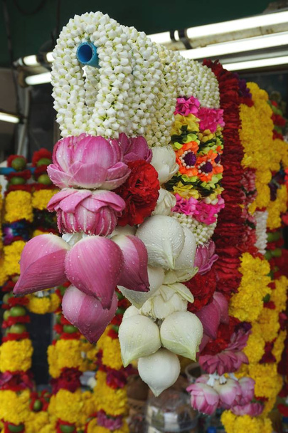 Detail aus bunten Blumengirlanden aus rosa und weißen Lotusblüten und gelben Chrysanthemenblüten. Anhänger kaufen die Blumen als Opfergaben für das Gebet in einem nahe gelegenen Hindu-Tempel in Bangkok Thailand - Foto, Bild