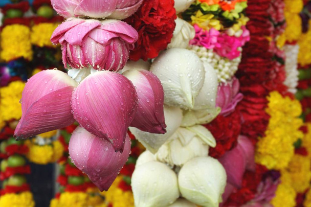 Nahaufnahme bunter Lotusblumen und Chrysanthemengirlanden, die als Opfergaben religiöser Anhänger auf einem Markt in der Nähe eines hinduistischen Tempels in Bangkok in Thailand angeboten werden - Foto, Bild