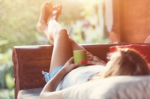 Chica tomando café / té y disfrutando del amanecer / atardecer en el jardín
. - Foto, imagen
