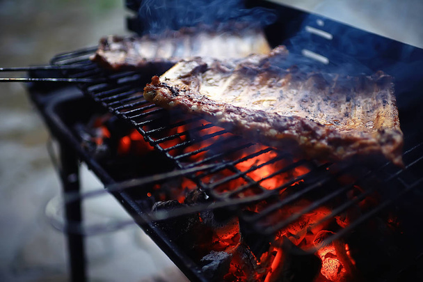 pork ribs on the grill cooking coals / fresh meat pork cooked on charcoal, summer home cooked meal, grilled ribs - Фото, изображение
