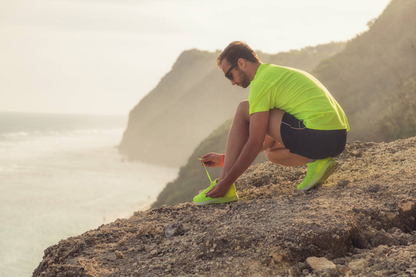 Tying running / jogging sneakers on a cliff near the sea / ocean. - Photo, Image