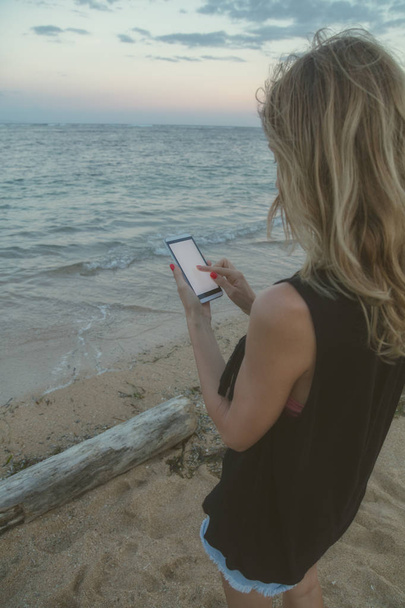 Girl using cellphone on a tropical exotic beach. - Фото, зображення