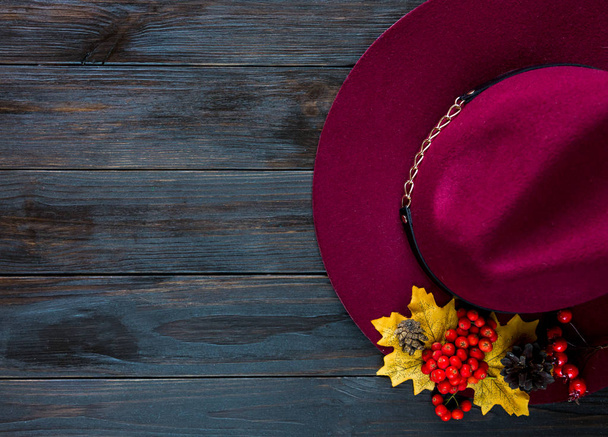 Composição de outono com marsala ou chapéu de borgonha e folhas em fundo de madeira marrom. Queda, conceito de mudança de estação
 - Foto, Imagem