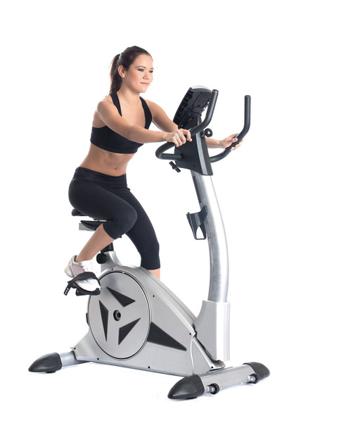 Young brunette woman on bike exerciser - Foto, afbeelding