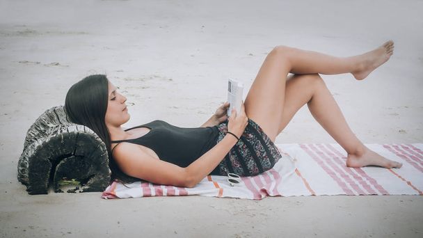Beautiful young woman lying on tropical beach, reading books. Koh Tao, Thailand - Fotó, kép