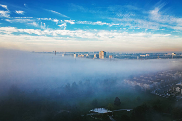 Foggy morning in Toronto city, Canada. Rays of early rising sun.  Landscape aerial top view with urban street covered with thick fog. Day white transparent mist in Canadian metropolia at sunrise.  - Photo, Image