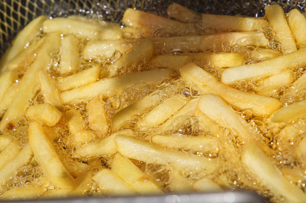 Картошка фри готовится в горячем масле в специальной металлической сетке. Крупный план. Фоновое изображение
 - Фото, изображение
