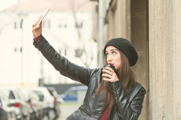 Chica urbana sosteniendo un teléfono celular y café al aire libre
. - Foto, imagen