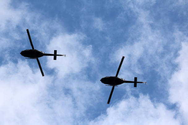 ein fliegendes schwarzes Helikopterflugzeug während des Fluges bei blauem Himmel  - Foto, Bild