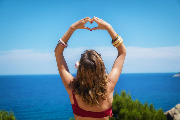 Girl holding heart - shape with ocea / sea background. - Foto, immagini