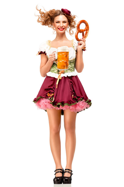 Creative concept photo of Oktoberfest waitress wearing a traditional Bavarian costume with beer and pretzel isolated on white background. - Zdjęcie, obraz