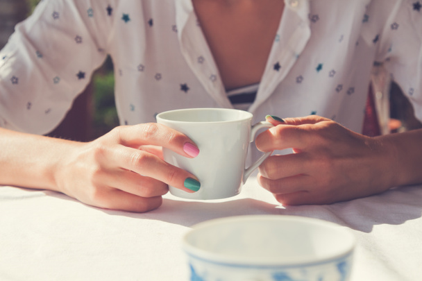 taza de café sosteniendo por una hembra en la mesa al aire libre
. - Foto, imagen