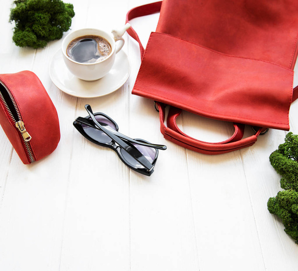 Красный кожаный рюкзак с аксессуарами на белом фоне
 - Фото, изображение