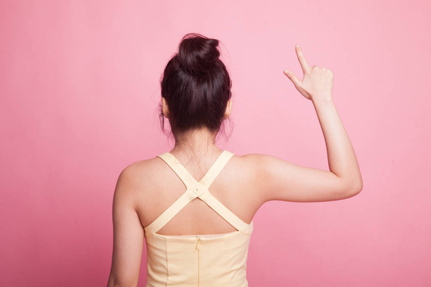 Back of Asian woman touching the screen with her finger on pink background - Zdjęcie, obraz