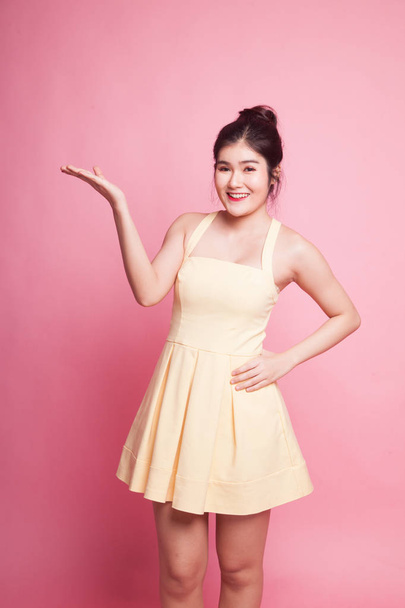Young Asian woman present with her hand on pink background - Foto, Bild