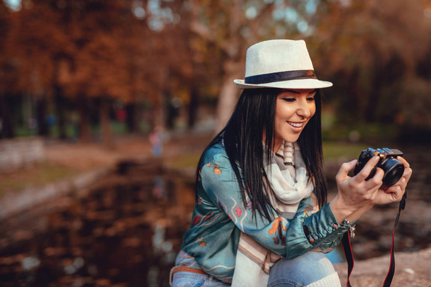 Γυναίκα κατέχει επαγγελματική, ψηφιακή κάμερα και τη λήψη φωτογραφιών στο Φθινοπωρινό πάρκο πόλης   - Φωτογραφία, εικόνα
