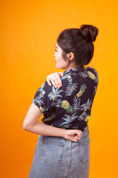 Young Asian woman got back pain in  tropical shirt on yellow background - Φωτογραφία, εικόνα