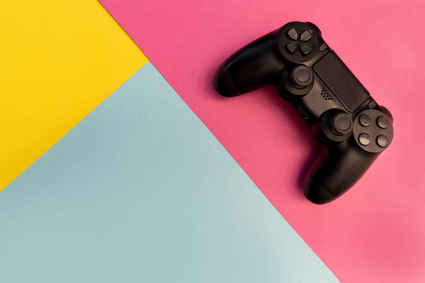 Contrôleur de jeux vidéo sur fond rose, bleu et jaune coloré
 - Photo, image