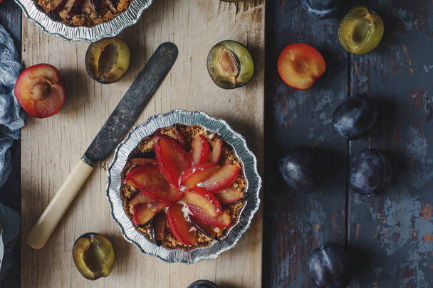 Homemade pies of fresh organic plums on wooden board and rustic table - Foto, imagen