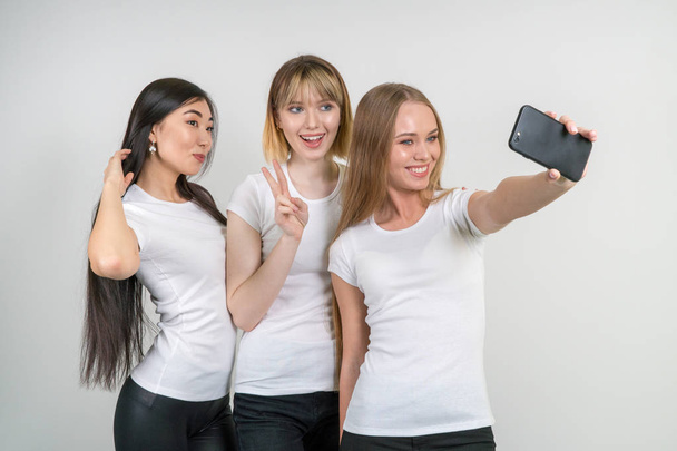 Meninas engraçadas bonitas fazer selfie. Meninas em camisetas brancas
. - Foto, Imagem
