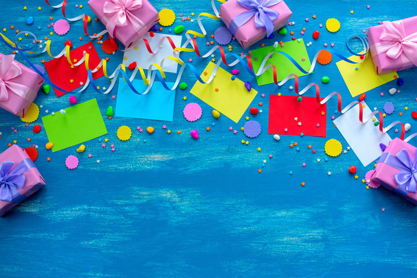 Slavnostní zářivě modré pozadí dekorace pro dovolenou barevné konfety hadovité papír dárky. Pohled shora na plochá místa ležela kopie - Fotografie, Obrázek