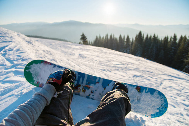 Oogpunt shot van een vrouwelijke snowboarder liggend op de sneeuw op de helling ontspannen na Paardrijden, genieten van prachtig uitzicht op de bergen van de winter en zonsondergang Pov concept - Foto, afbeelding