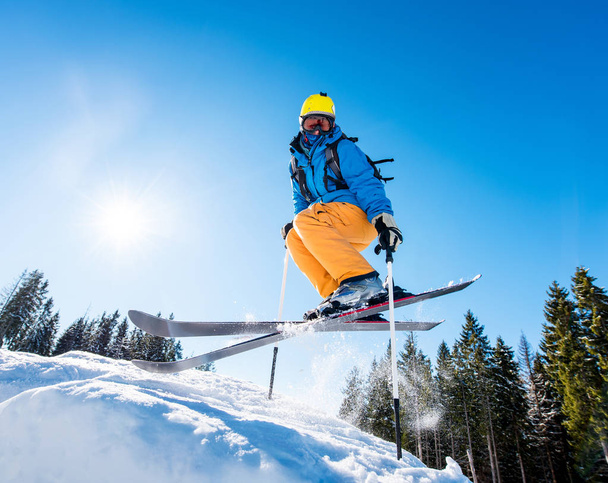 Matala kulma laukaus hiihtäjä värikkäitä pyydyksiä hyppäämällä ilmassa hiihto rinteessä auringonvalo äärimmäinen adrenaliini virkistys käsite
 - Valokuva, kuva