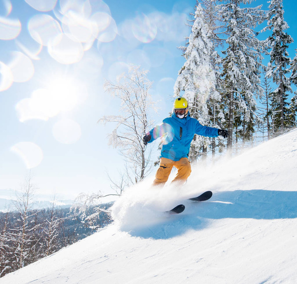 Shot of a male freerider skiing in the mountains on fresh powder snow on a beautiful sunny winter day - Foto, imagen