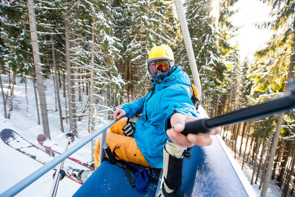 Scatto di uno sciatore che si fa un selfie con un bastone selfie mentre guida gli impianti di risalita verso la cima della montagna nella località sciistica invernale tecnologia persone attività sociale viaggio viaggio concetto di viaggio
. - Foto, immagini