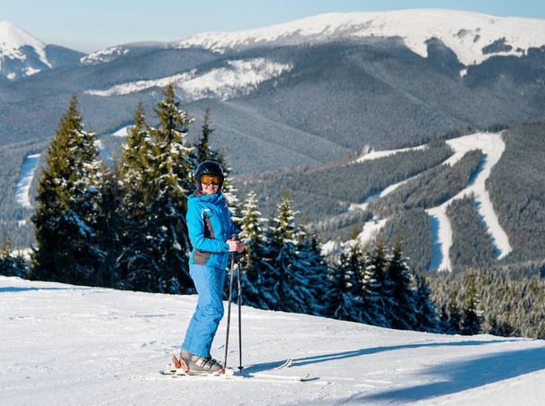 Πλήρες μήκος πλάνο του μια ευτυχισμένη γυναίκα σκιέρ σκι στις πλαγιές το χειμώνα σκι θέρετρο στο ηλιόλουστο όμορφη μέρα. Βουνά, δάση, στις πίστες του σκι στο παρασκήνιο. ευτυχία δραστηριότητα αναψυχής έννοιας σπορ - Φωτογραφία, εικόνα